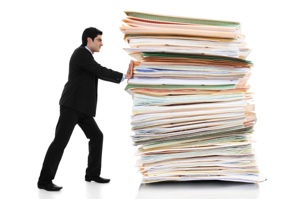 Stock image of businessman pushing a giant stack of documents isolated on white background