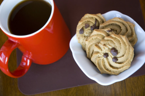 chocolate chip cookies in white plate with red cup coffee