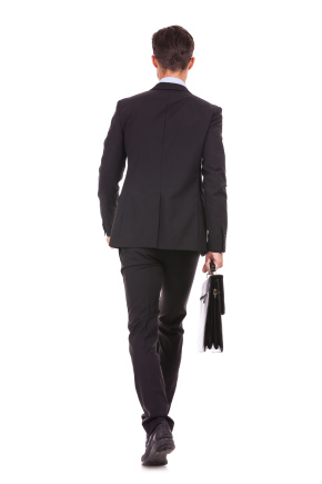 back view of a businessman holding a briefcase and walking forward on white background