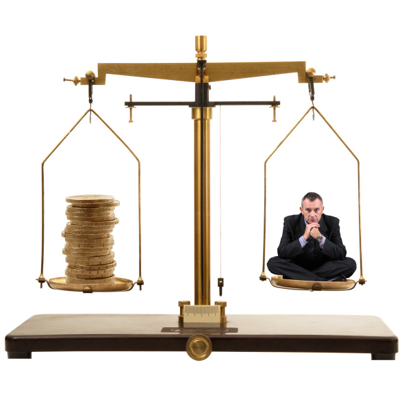 Businessman sitting on scales with stack of coins in other tray