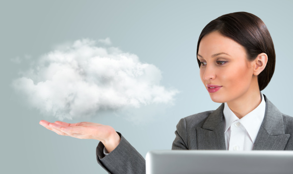Businesswoman at laptop with cloud floating above outstretched hand