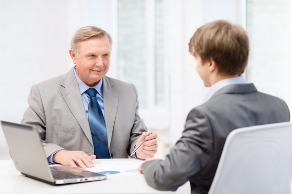 Older man and younger man having meeting at desk