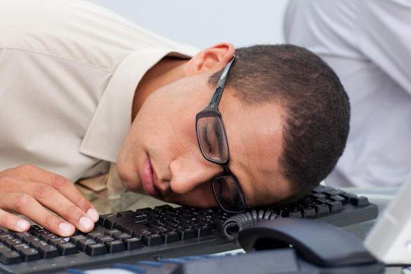 Young businessman sleeping on the keyboard in the office