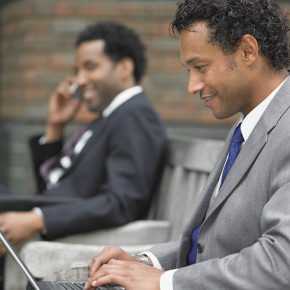 Two businessmen working on outdoor bench