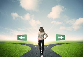 Businesswoman at crossroads, facing two paths