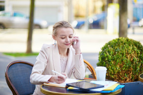 Young businesswoman using smartphone and tablet at outdoor cafe