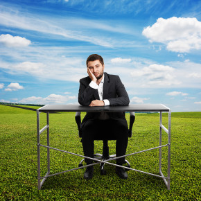Sad businessman sitting at desk outdoors and looking straight ahead