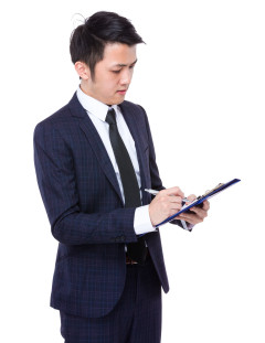 Businessman writing on clipboard
