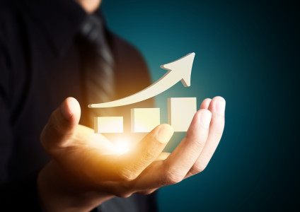 Arrow rising above ever larger blocks in businessman's hand, indicating growth