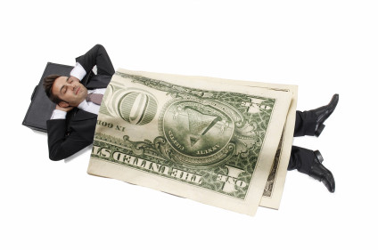 Businessman sleeping with a giant dollar bill for a blanket
