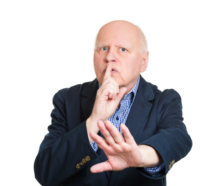 Older man with finger on lips and other hand out in "shush" gesture