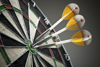 Three darts hitting a target bull's-eye