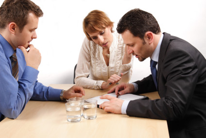 Three people having discussion at table over document and water glasses