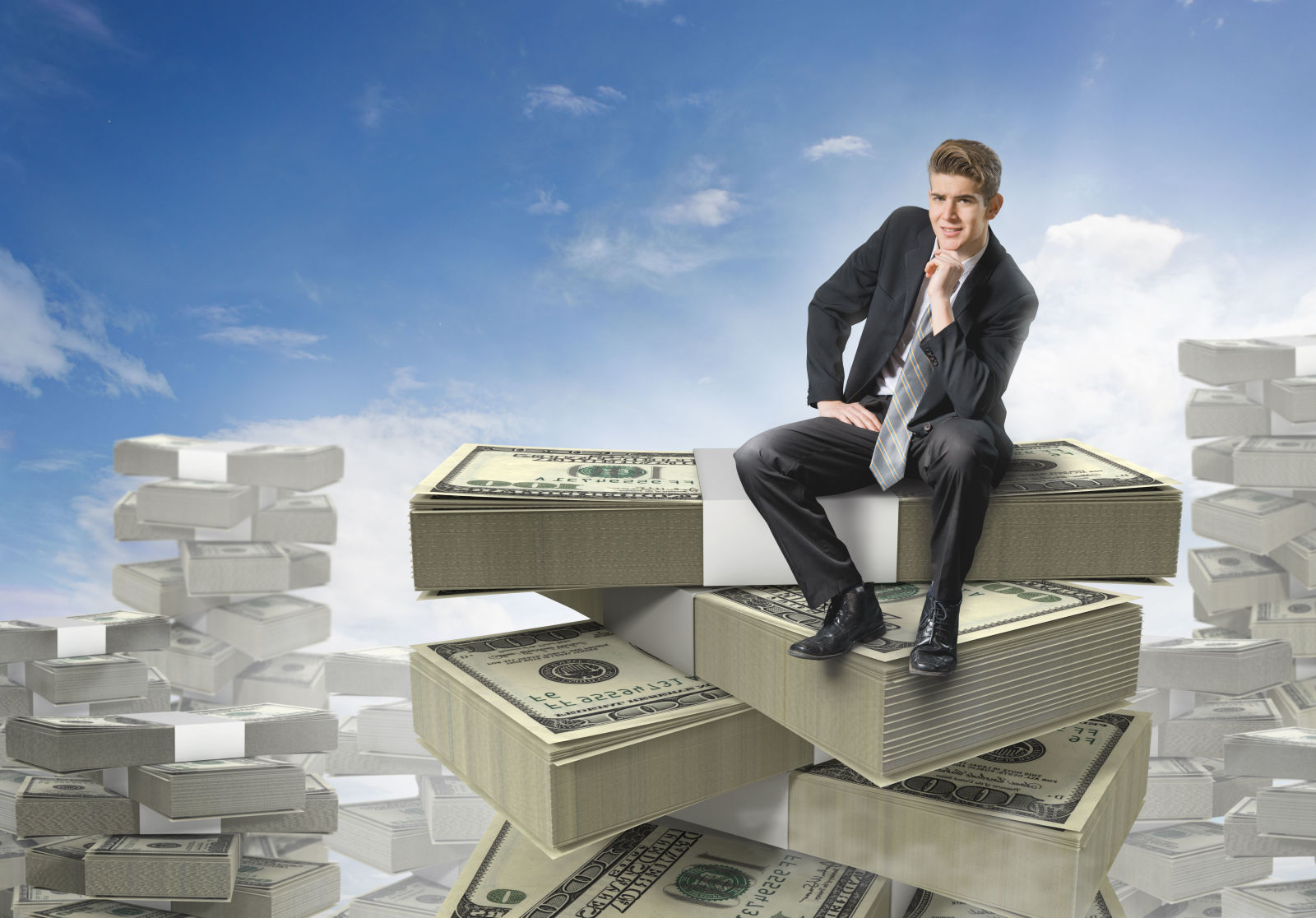 Businessman sitting on stacks of paper currency
