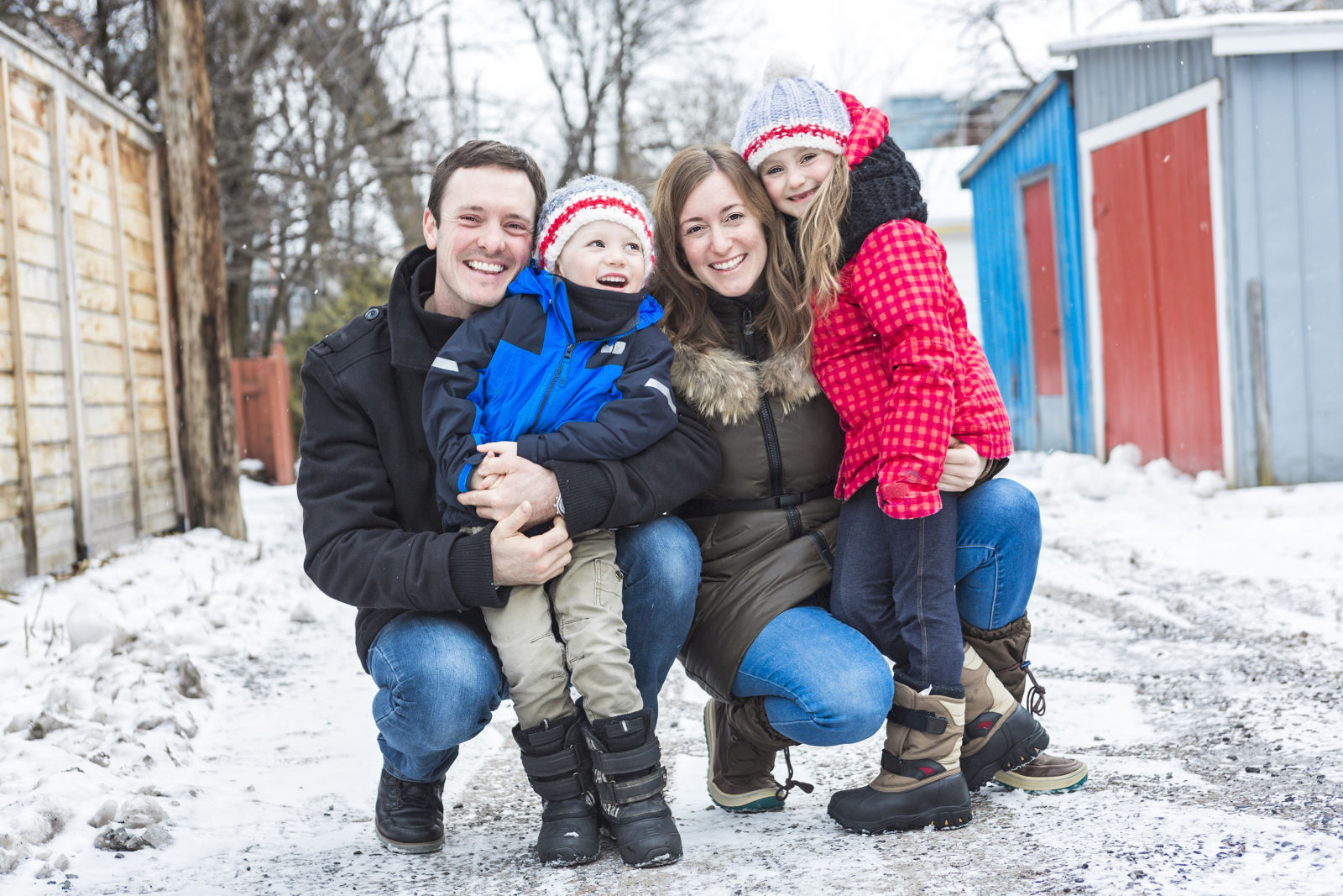 Happy family of four outdoors in winter clothing on snow