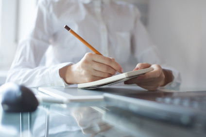 Woman's hand using a pencil on notepad