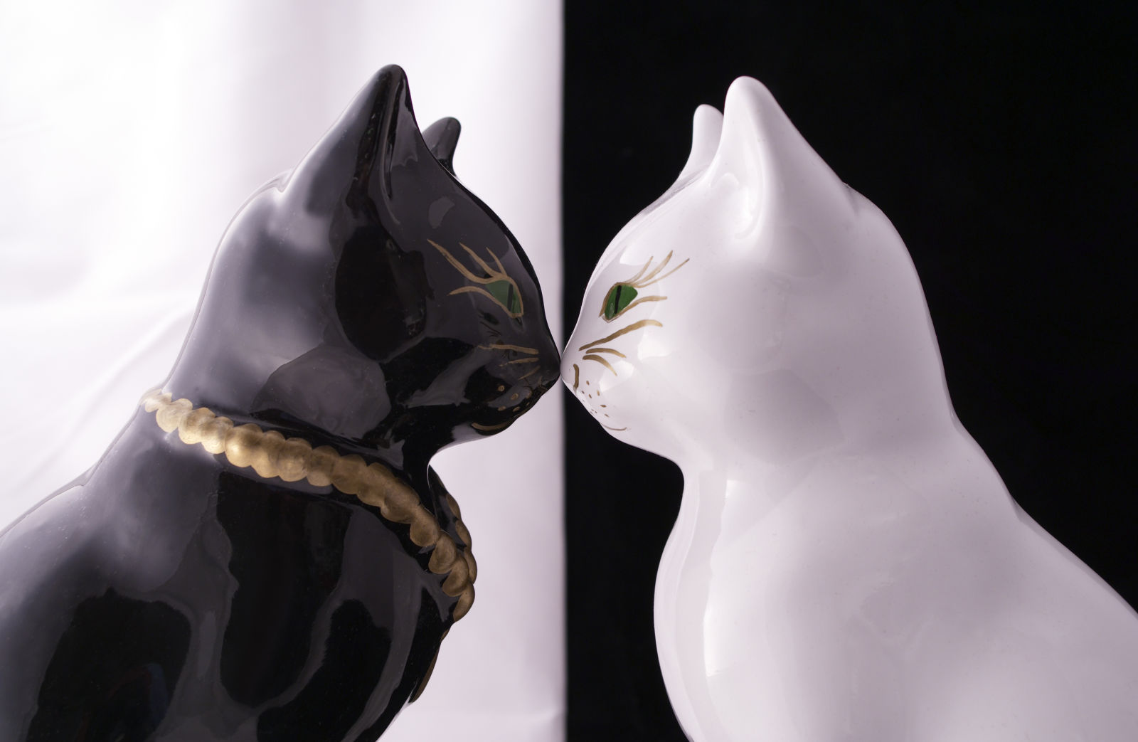 Black cat statue and white cat statue, nose to nose