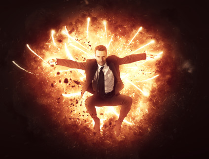 Businessman bursting through flames and fireworks