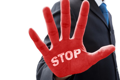 Businessman in dark gray suit raise his hand in action of stop and word "stop" on his red palm