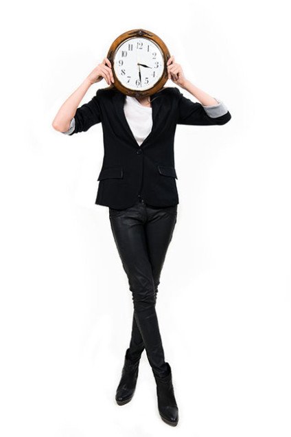 Businesswoman holding clock in front of her face