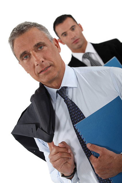 Older businessman with younger businessman trailing behind him