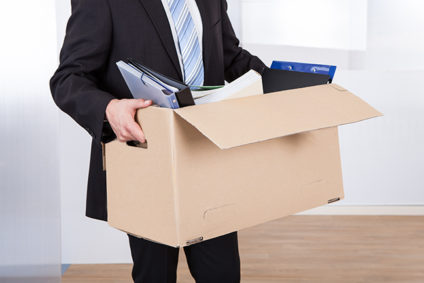 Midsection of businessman moving out with cardboard box from office