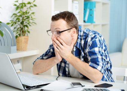 Man staring at computer screen in shock