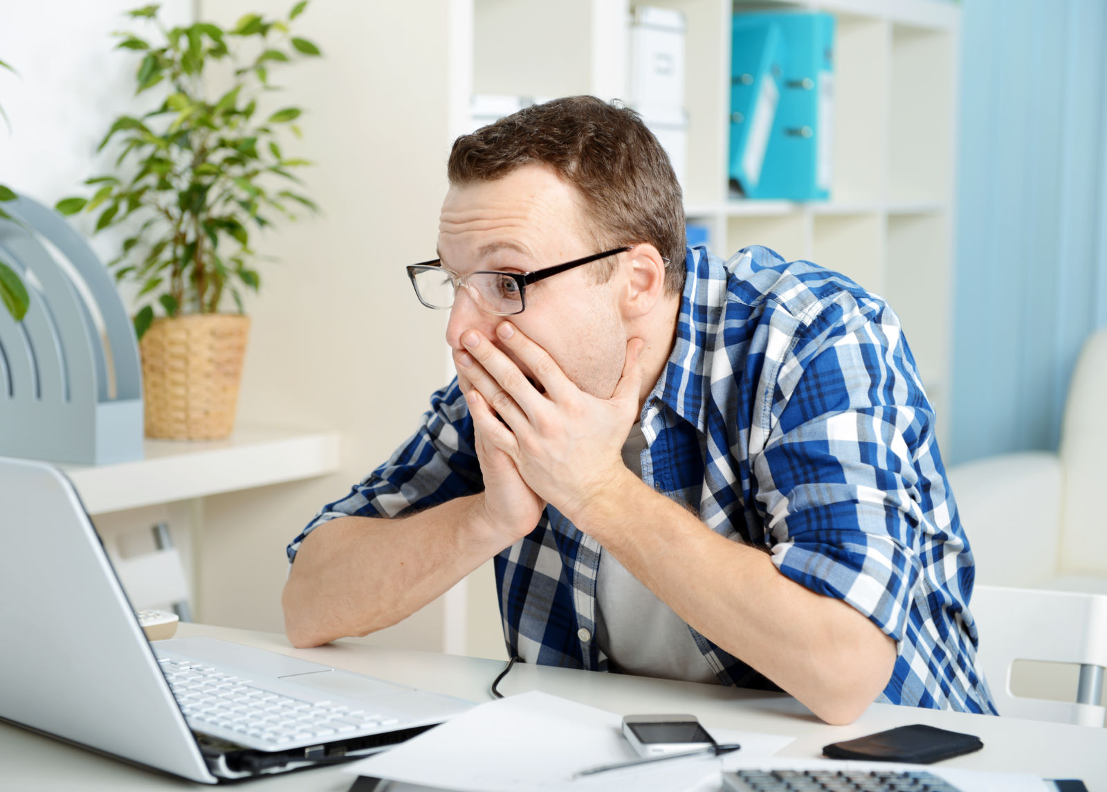 Man staring at computer screen in shock