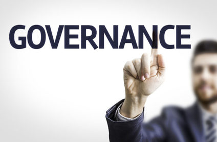 Businessman pointing to transparent board with text: Governance