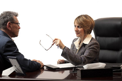 Woman executive coaching a male employee across desk