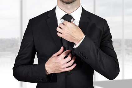Businessman in black suit straightening necktie