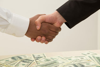 Handshake over currency scattered on table