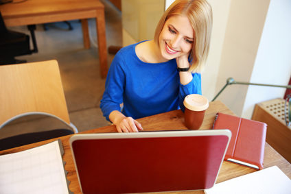 Young smiling woman using red laptop in office