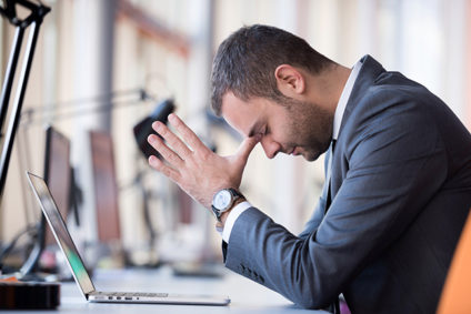 Young businessman with forehead resting on hands