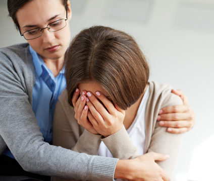 A woman hugs another woman, who is crying