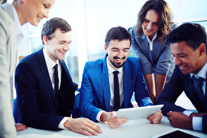 4 happy co-workers looking at man's tablet