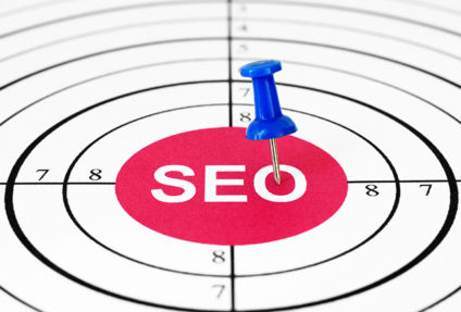 Blue pushpin in word "SEO" at center of a target