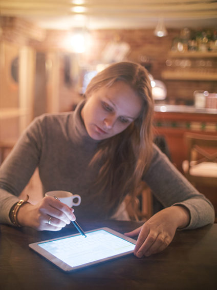 Young woman using a tablet PC and stylus at a cafe