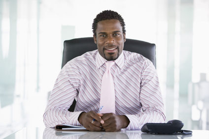 Businessman sitting at desk, looking forward and smiling