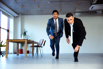 Two businessmen running together in office