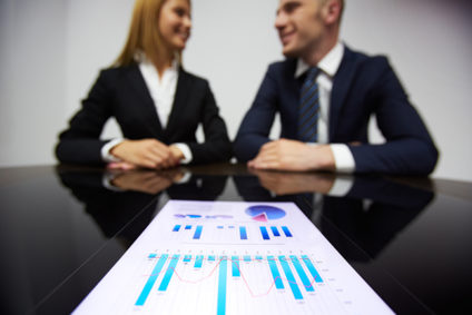 Image of charts in foreground and business partners in background