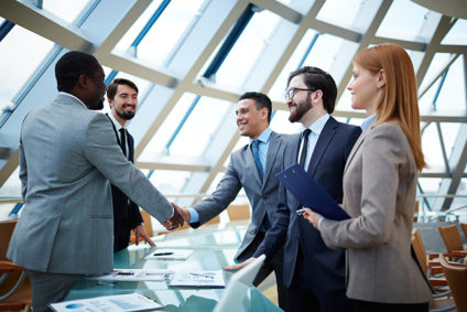 Five businesspeople shaking hands under office skylight