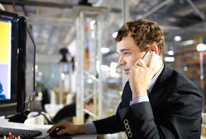 Young man working at a computer and talking on a phone