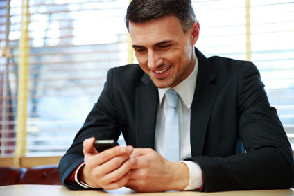 Happy businessman using smartphone at office