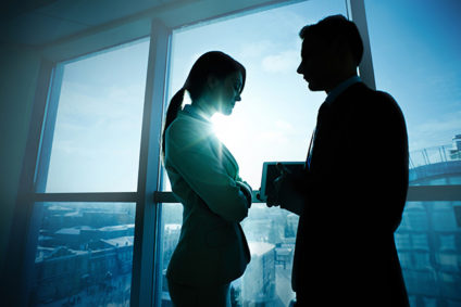 Woman and man silhouetted against office window