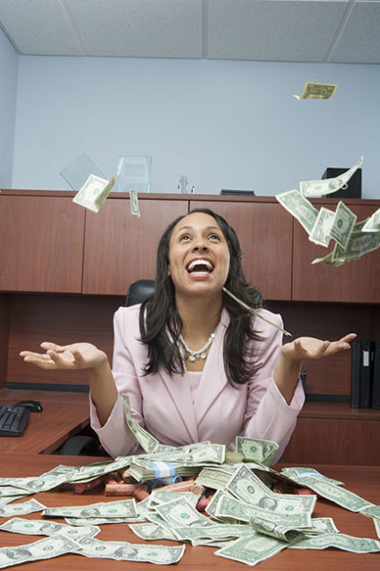 Businesswoman throwing money into air in office