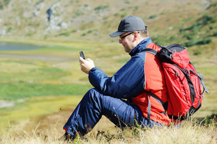 Man sitting on mountain and searching for mobile signal