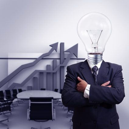 Businessman with light bulb for head in front of conference table and upward-trending chart