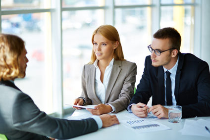 Two serious business partners listening attentively to young man at interview in office