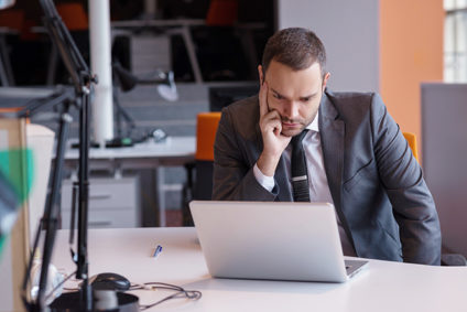 Young businessman staring at laptop computer in office
